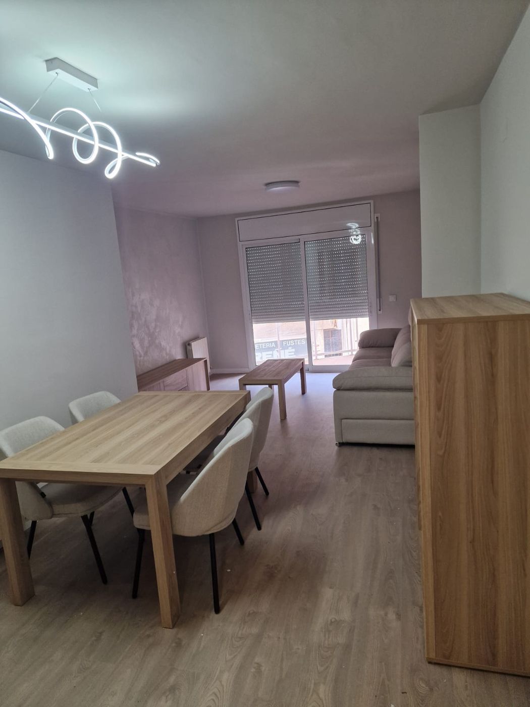 Salón comedor reformado con suelo laminado y lámpara LED de diseño