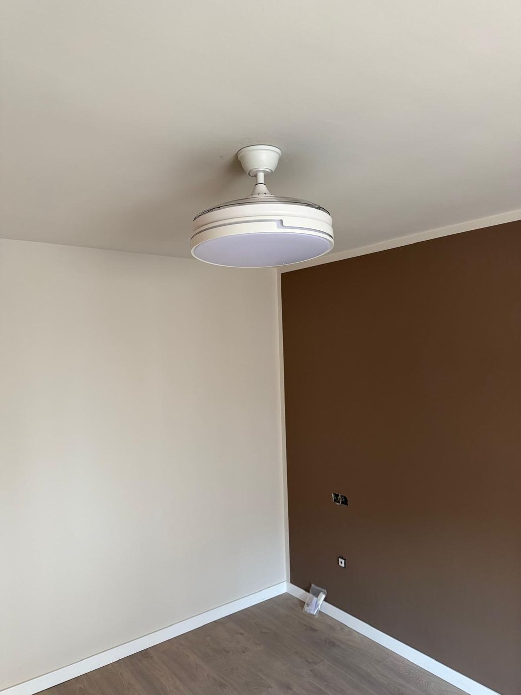 Ventilador de techo con luz LED instalado en un dormitorio pintado